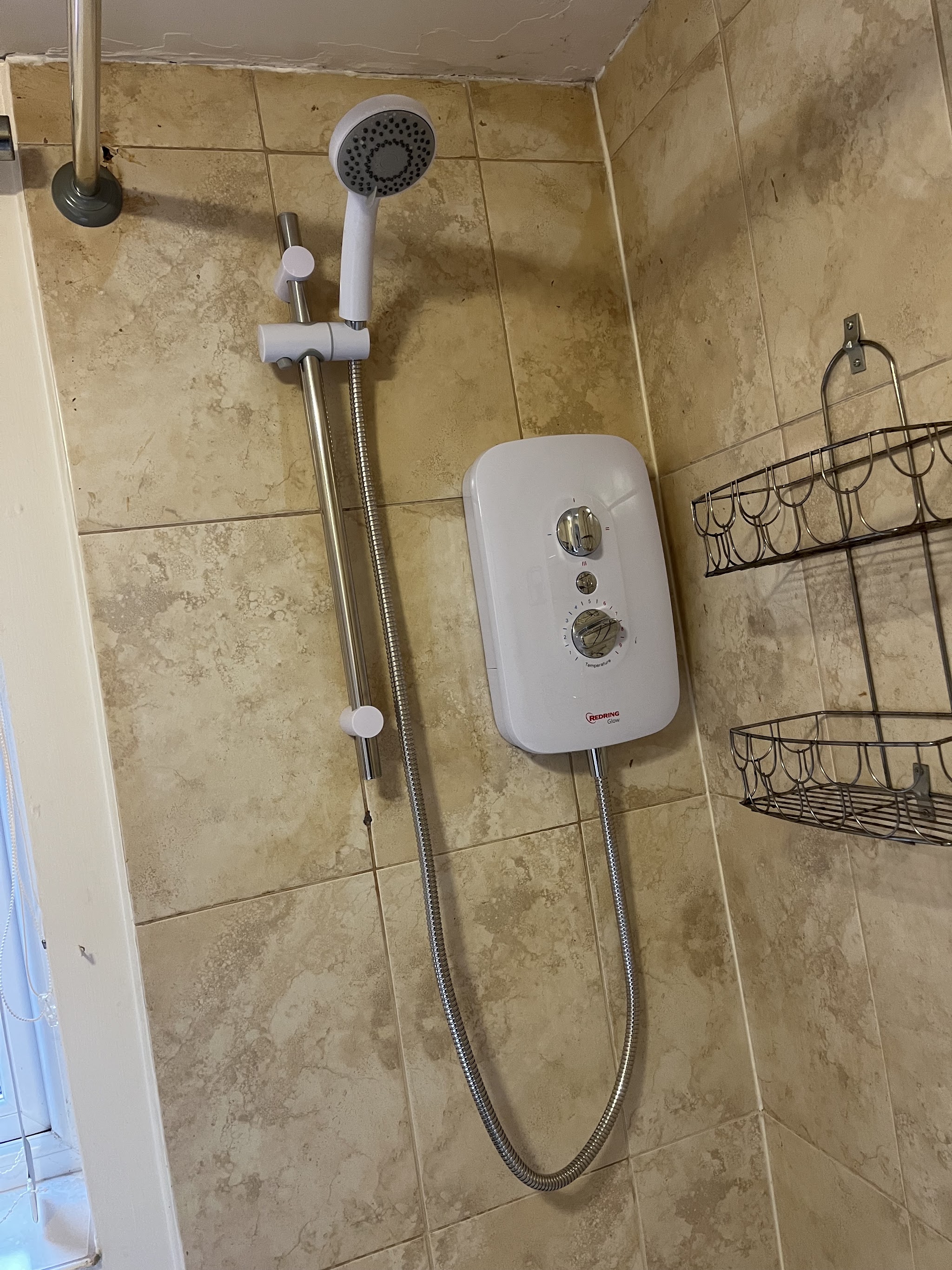 White electric shower fitted in a tiled bathroom