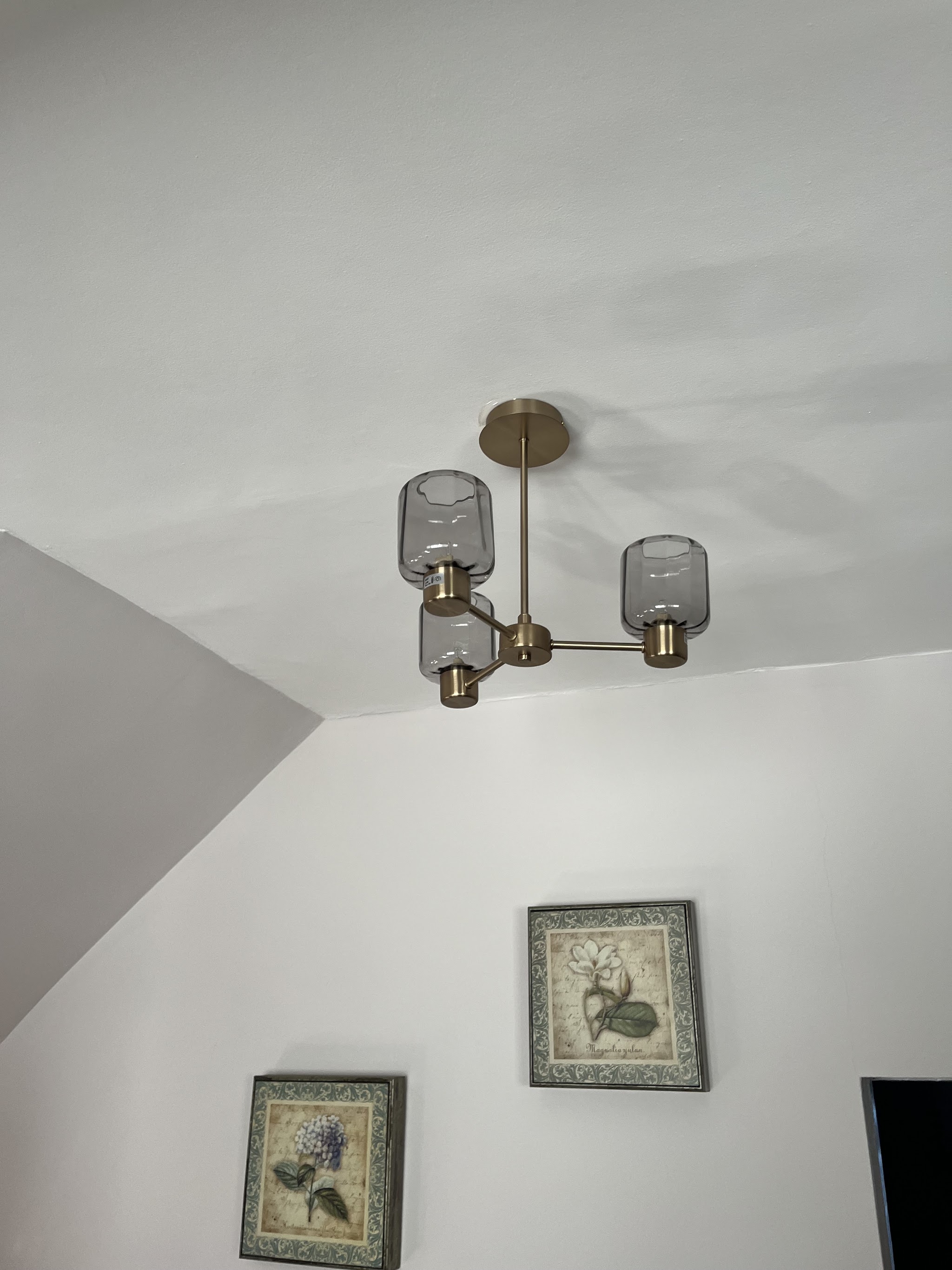 Brass pendant light with smoked glass shades on a white ceiling